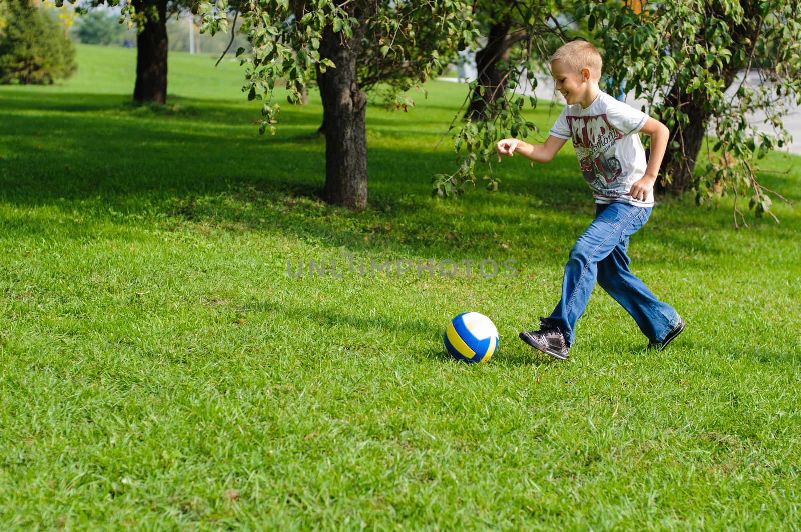 Young boy playing with his ball in the grass outdoors