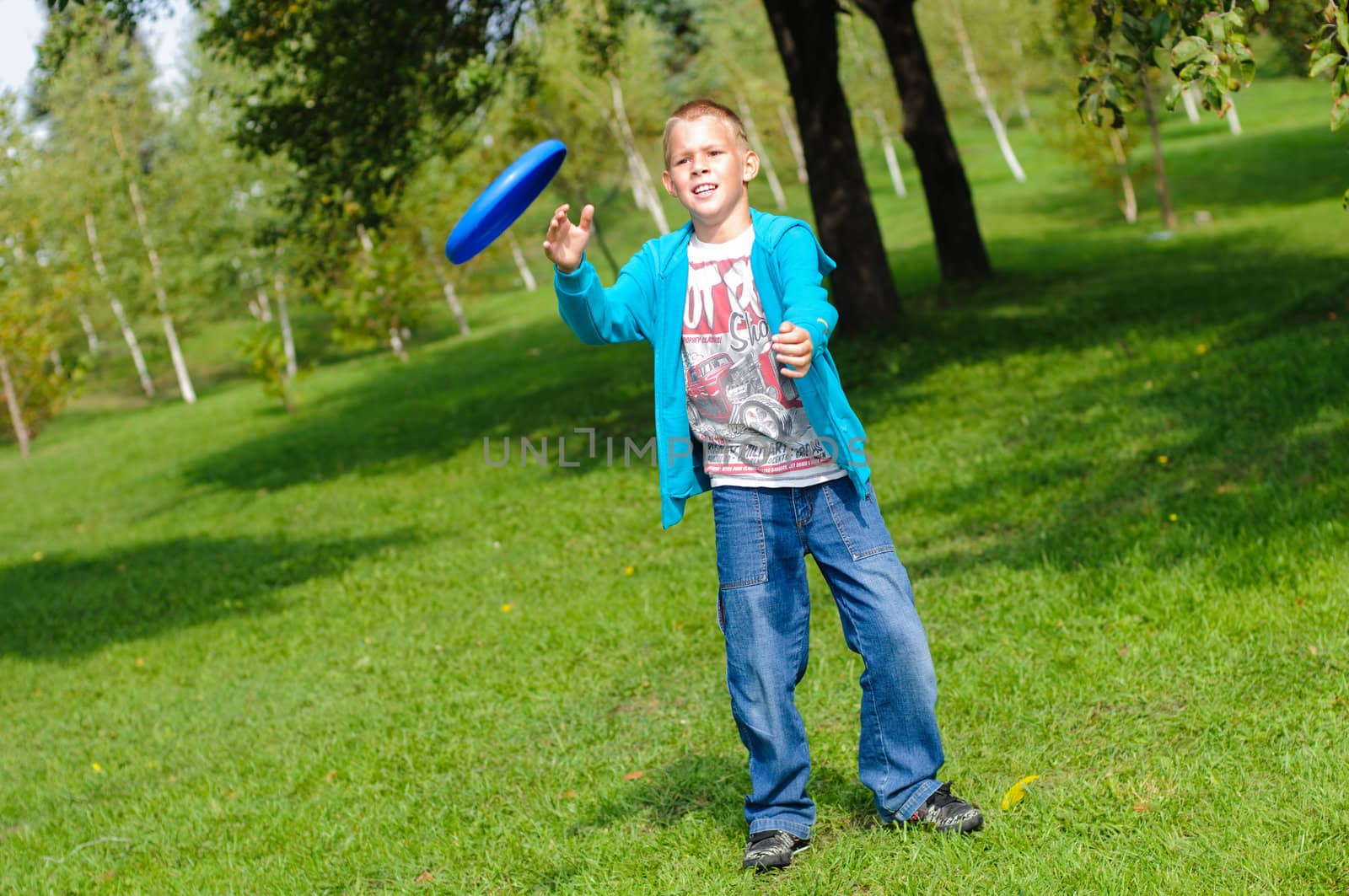 Little boy playing frisbee on green grass