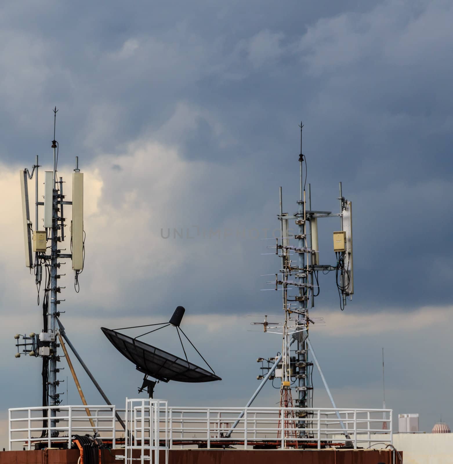 Satellite dish and mobile phone communication repeater antenna in cloudy sky