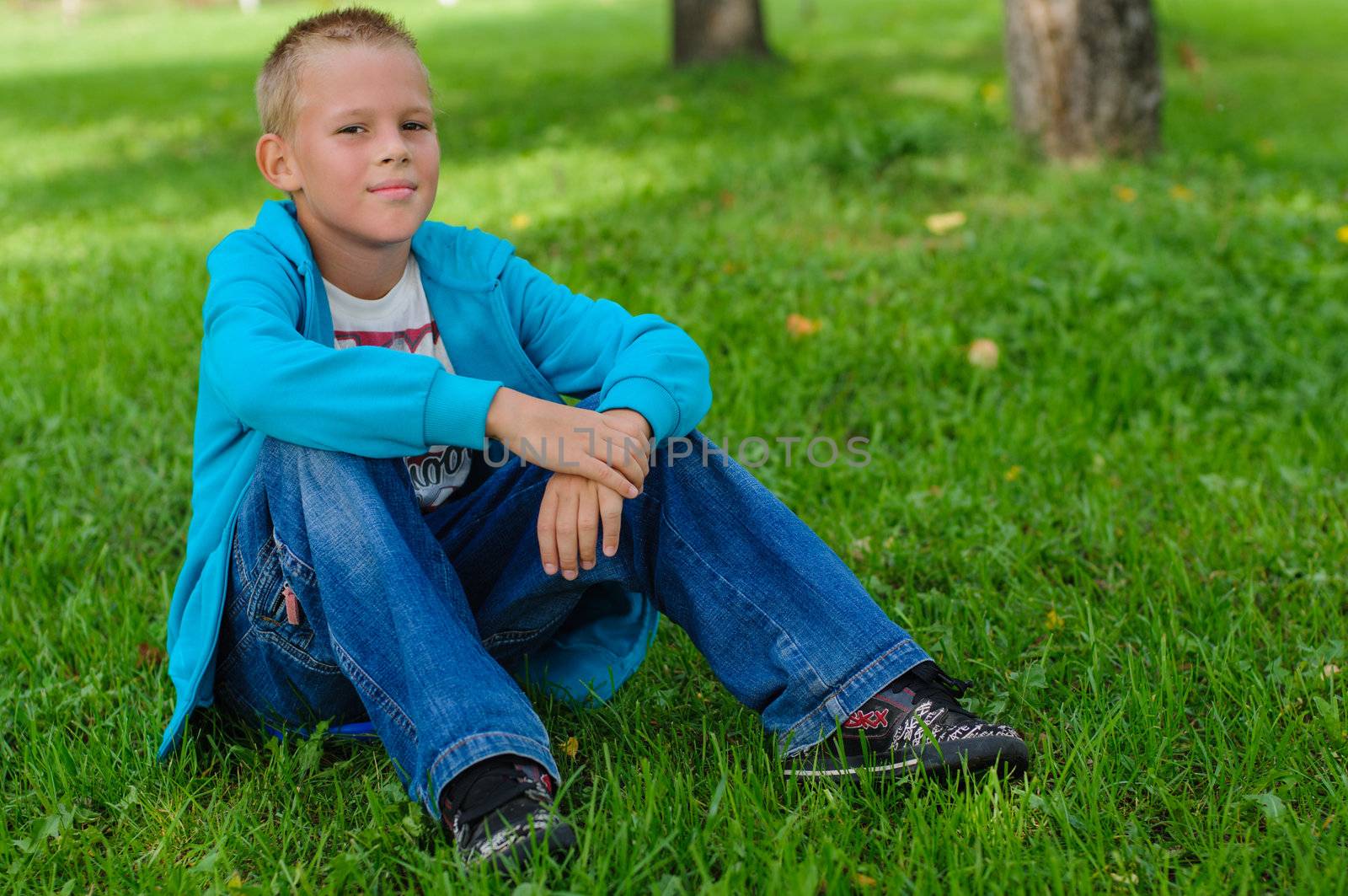 Young boy in jeans sitting on the grass