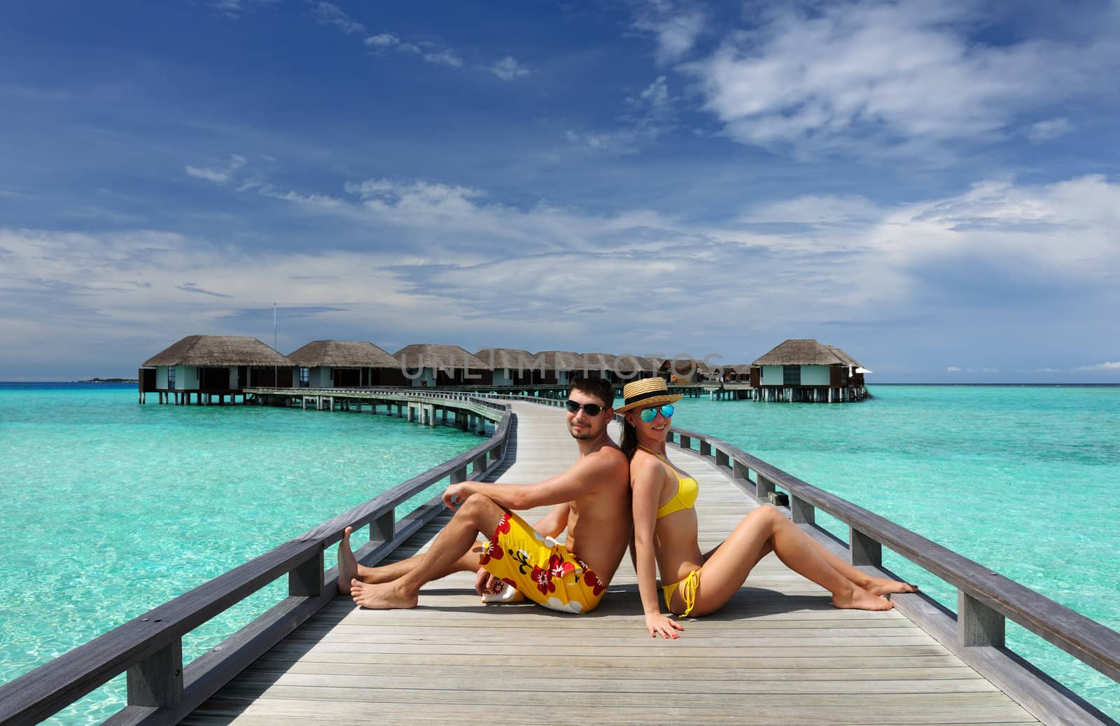 Couple on a tropical beach jetty at Maldives