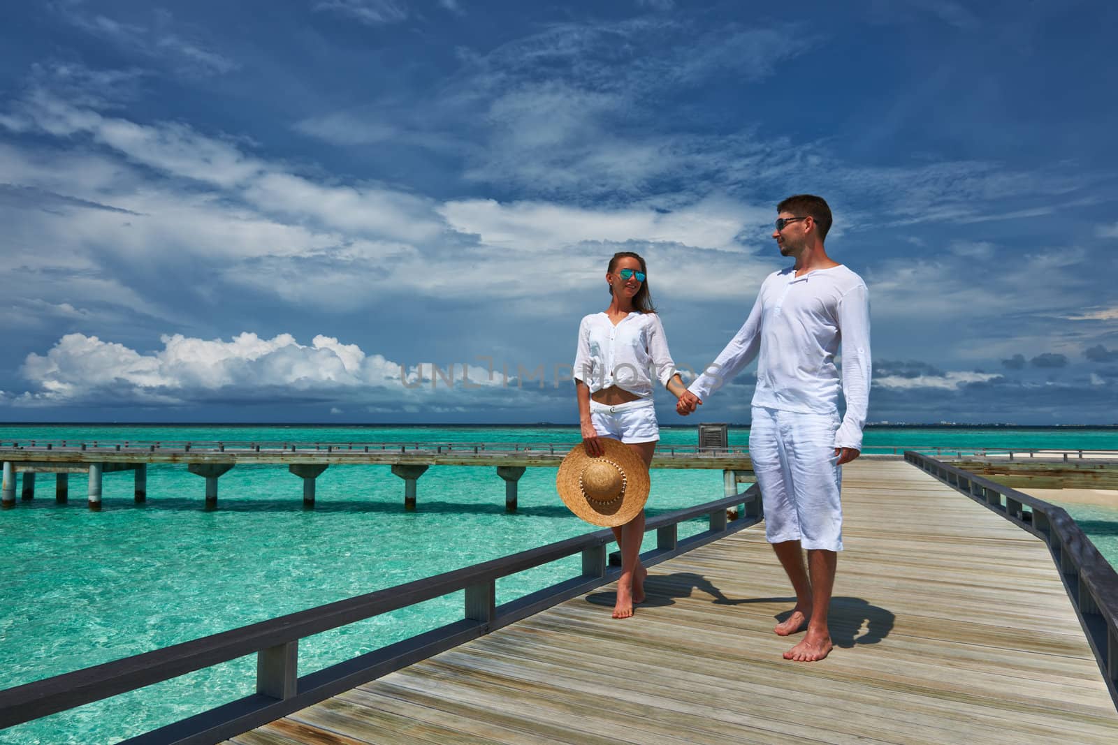 Couple on a tropical beach jetty at Maldives