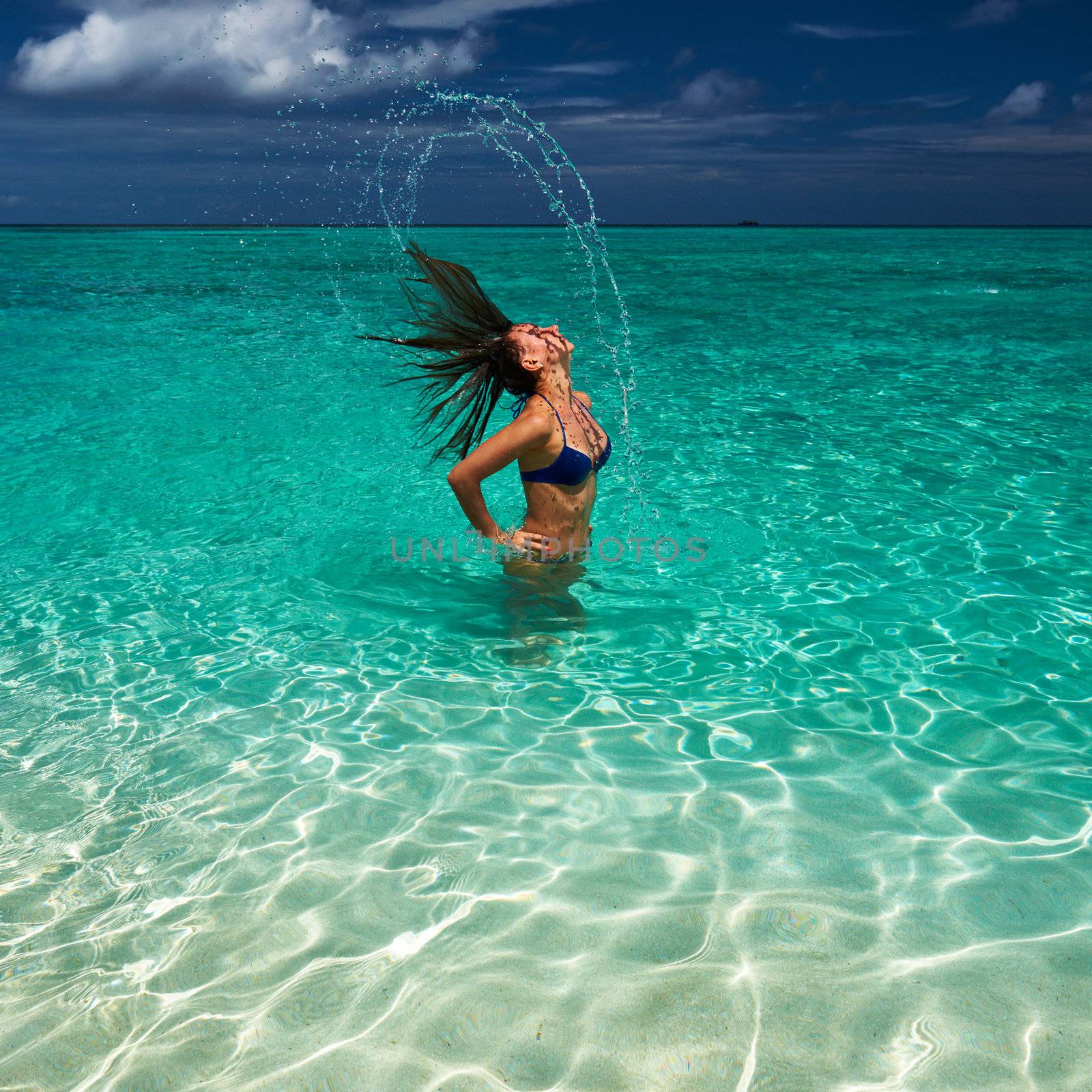 Woman splashing water with hair in the ocean by haveseen