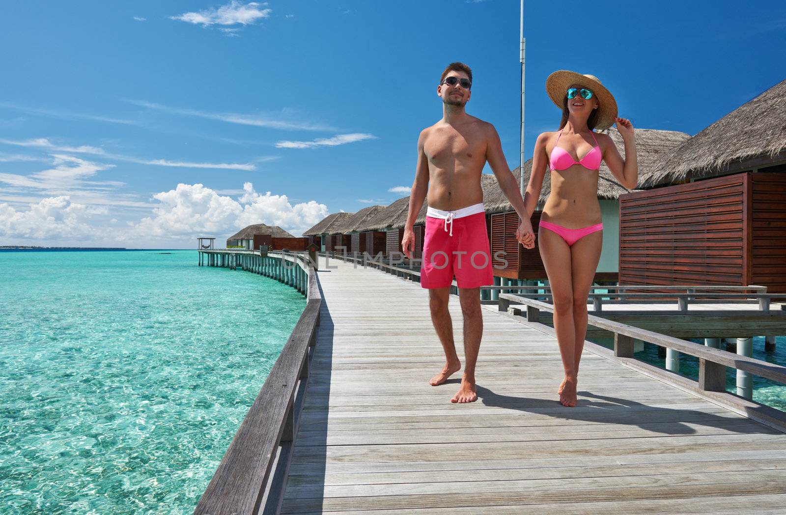 Couple on a tropical beach jetty at Maldives