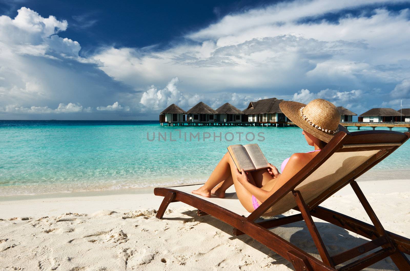 Young woman reading a book at beach by haveseen