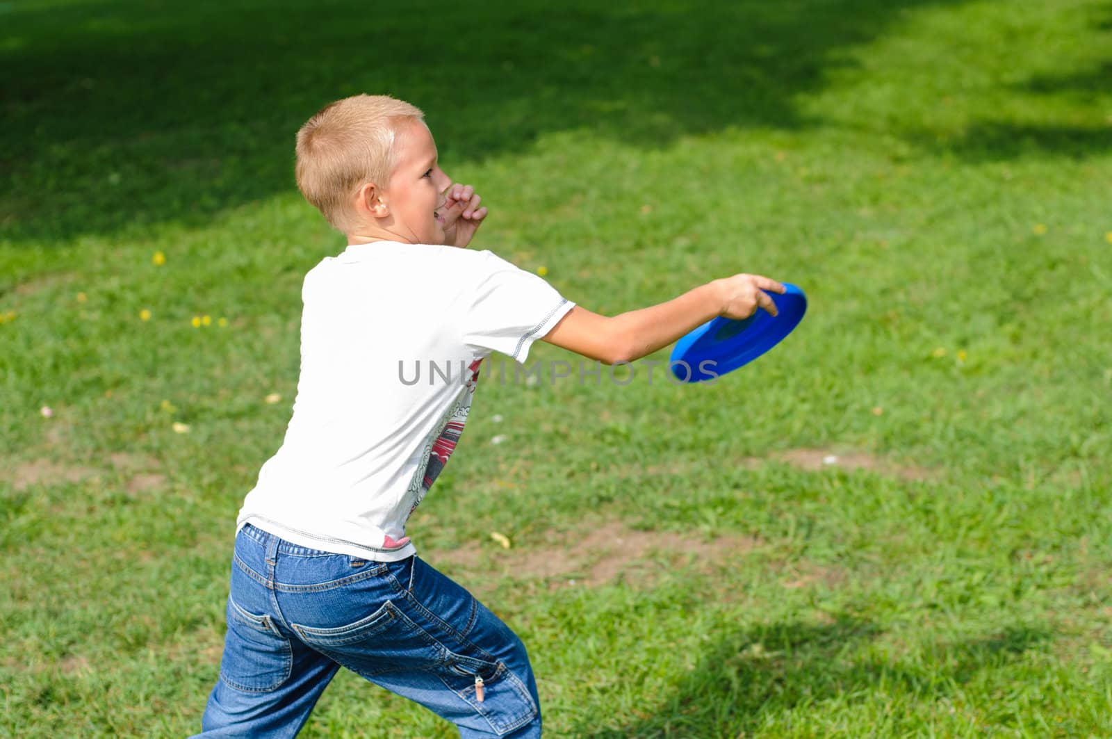 Little boy playing frisbee on green grass