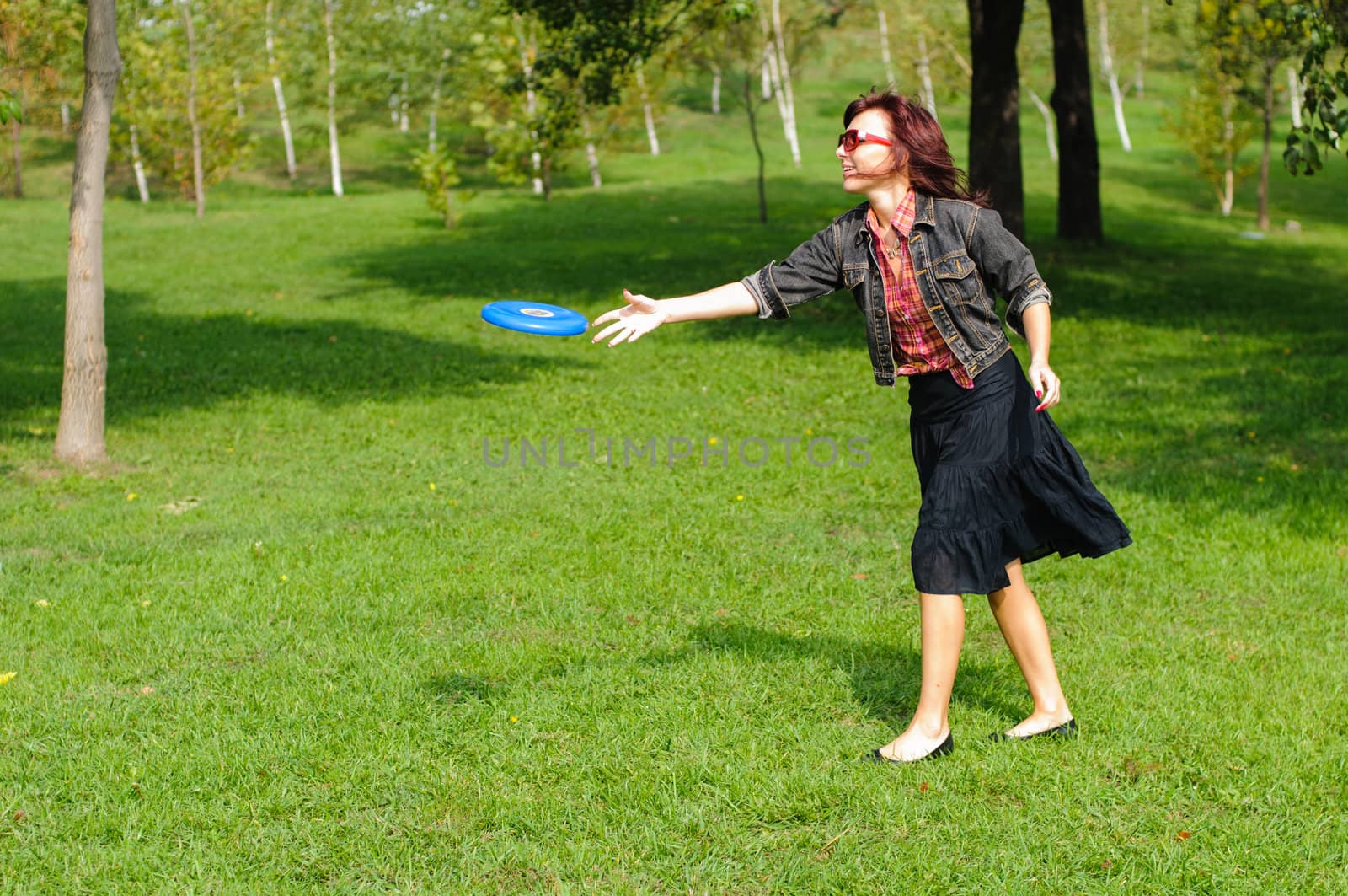 Young woman having fun with frisbee in the parkin sunny summer day.