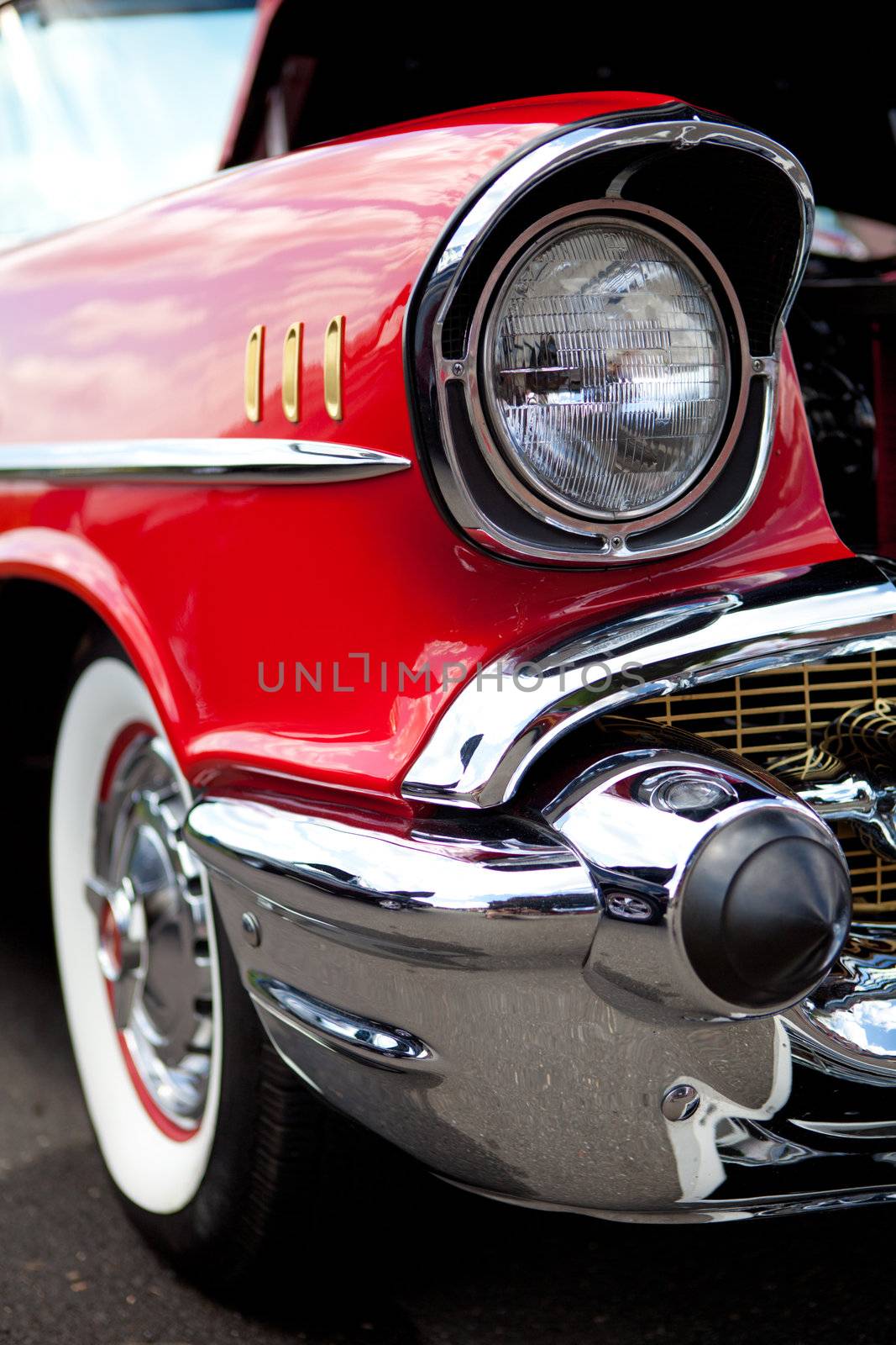 A closeup of the headlight and front bumper on a vintage American automobile.