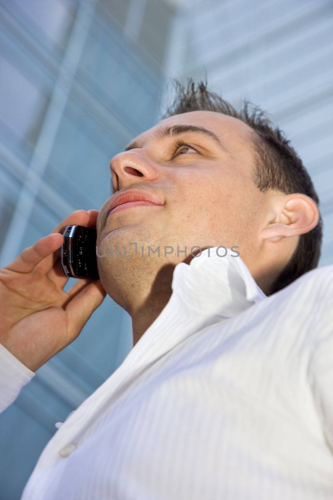 handsome businessman with cell phone in front of a modern office building (focus on lips)