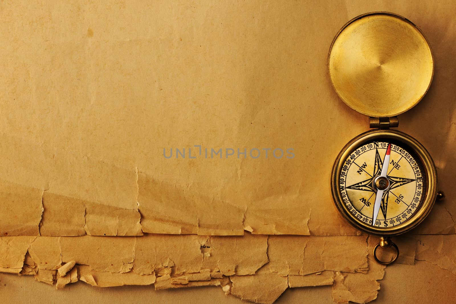 Antique brass compass over old paper background