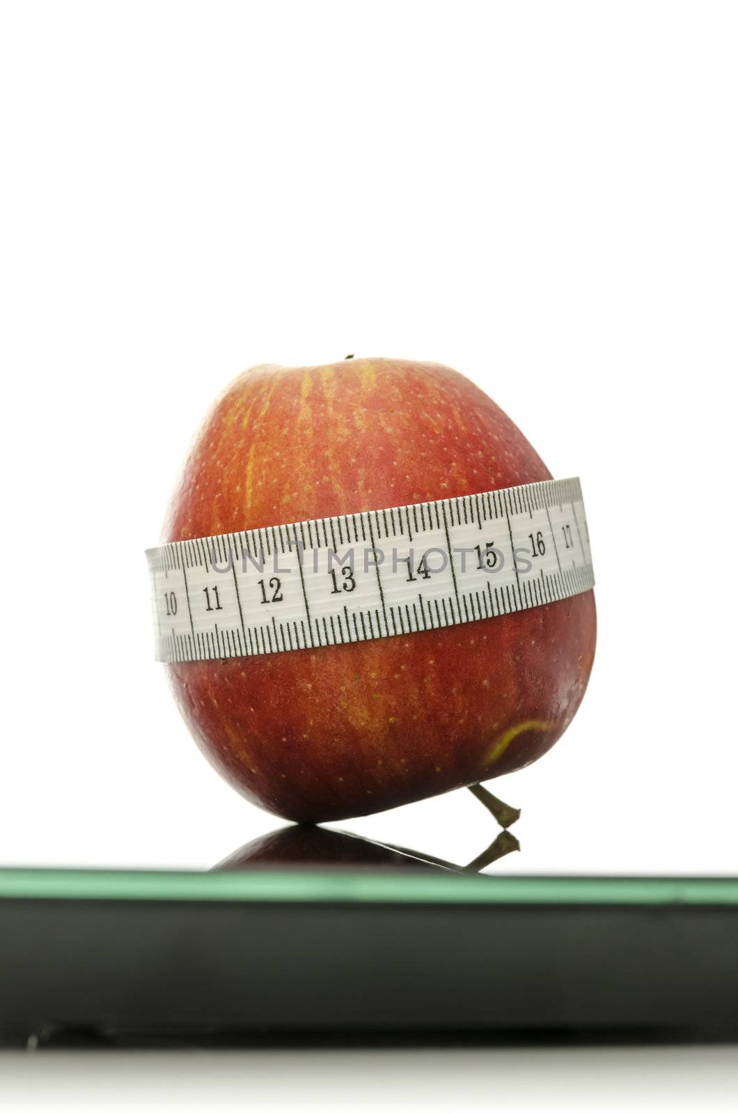 Apple wrapped with measuring tape on a digital scale. Weight loss concept. 