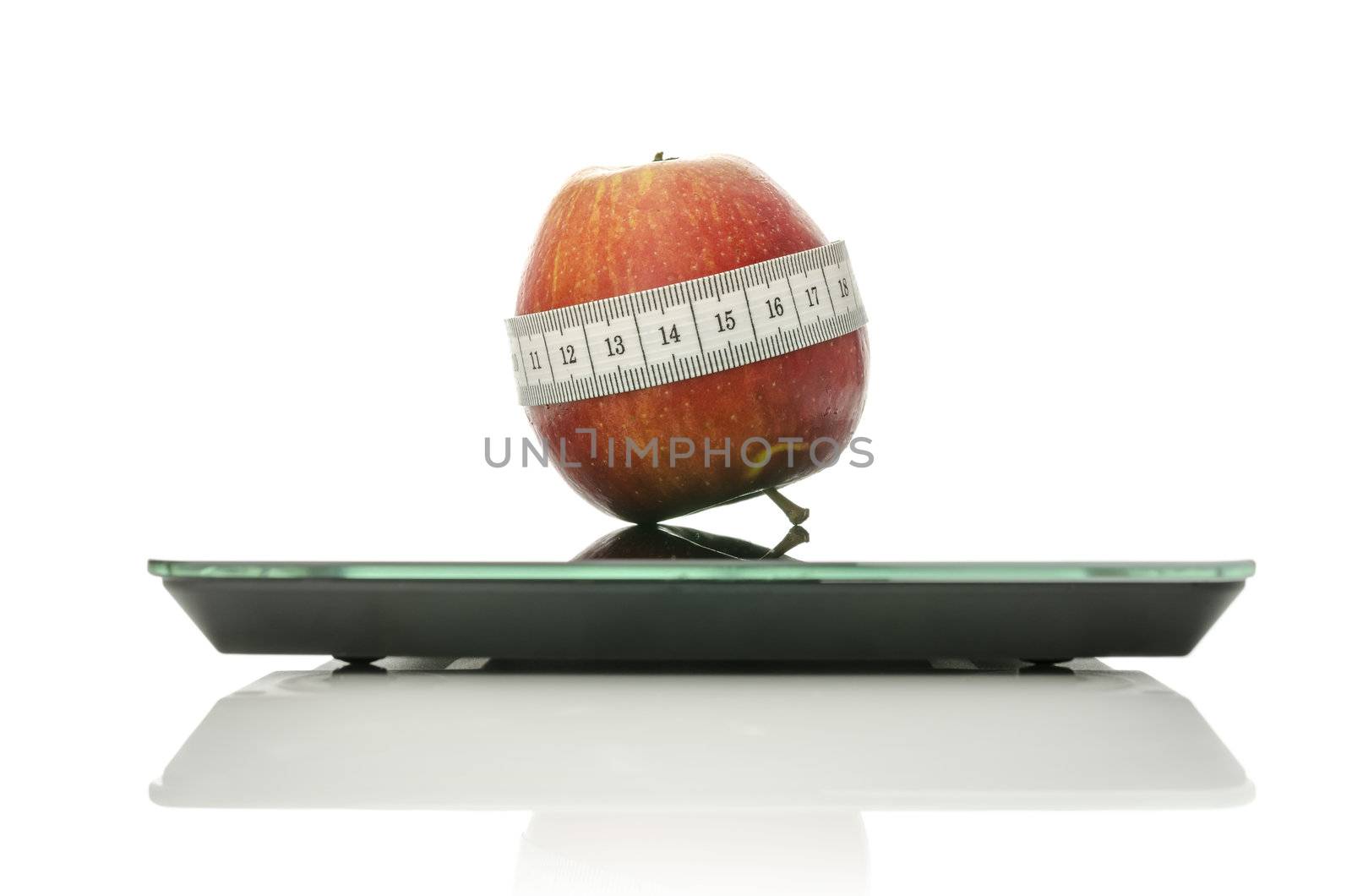 Apple wrapped with measuring tape on a digital kitchen scale. Isolated over white background.Concept of dieting and healthy eating.