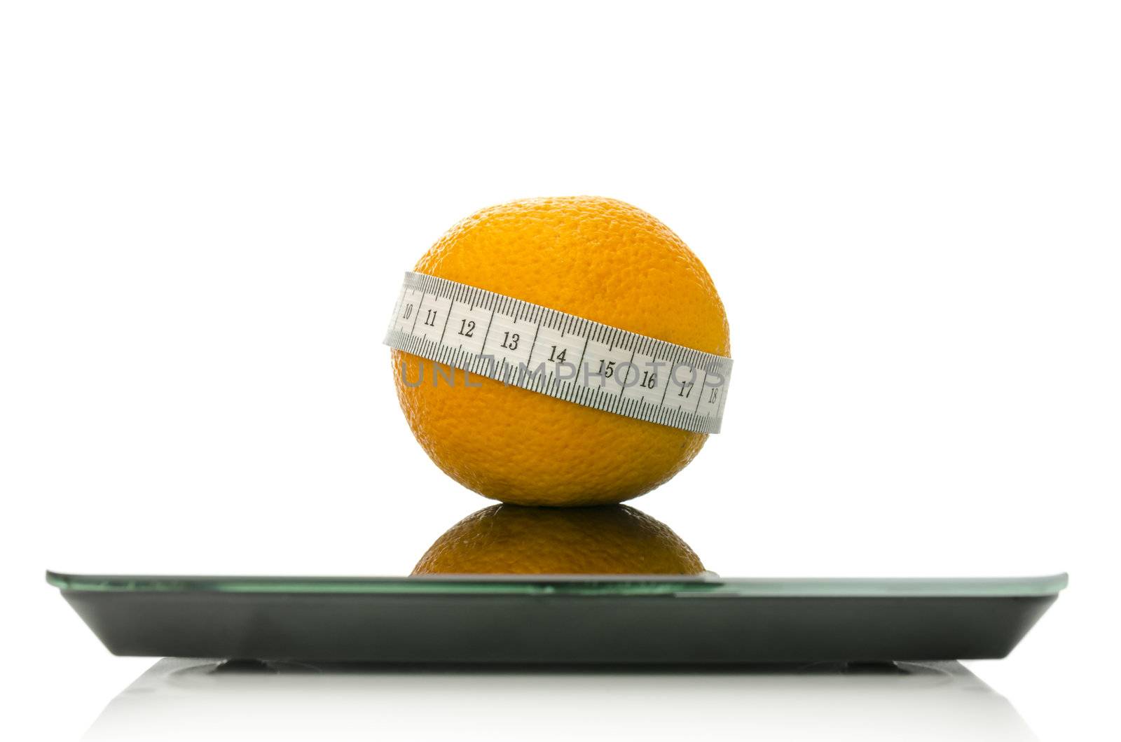 Orange fruit wrapped with measuring tape on a scale. Concept of dieting. Isolated over white background.