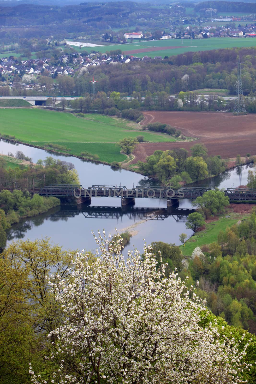 Scenic view of a lush green valley and farmland with a bridge crossing a river at the confluence of two canals