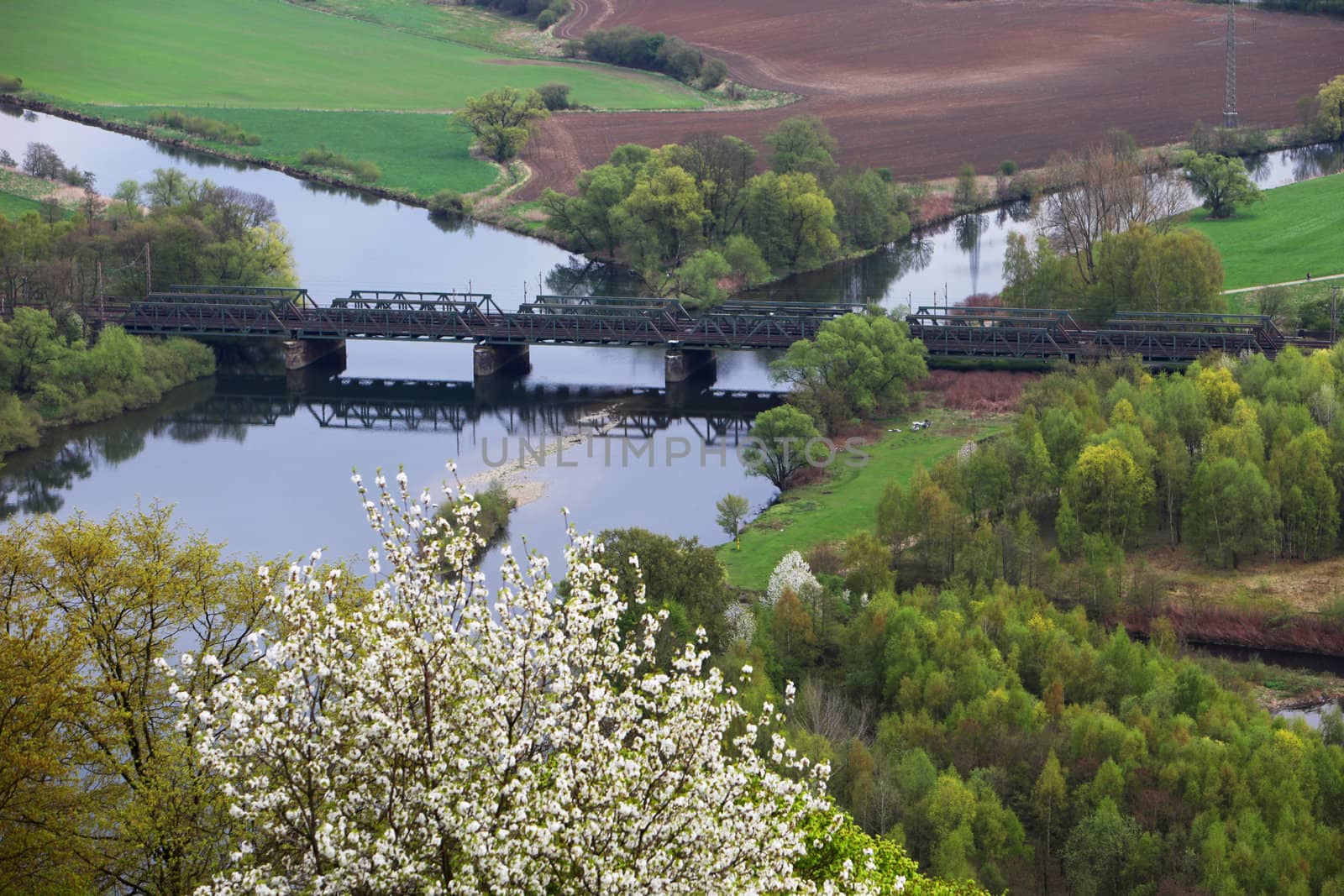 Scenic view of a lush green valley and farmland with a bridge crossing a river at the confluence of two canals