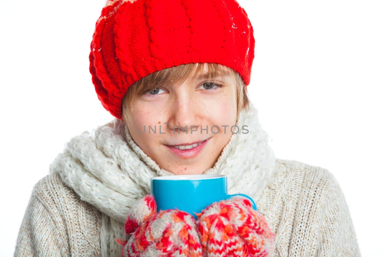 Portrait of young smiling cute teenager in a red hat and mittens with blue cup, isolated on white