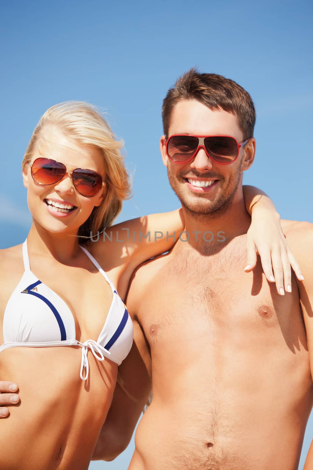 picture of happy couple in sunglasses on the beach. (focus on man)