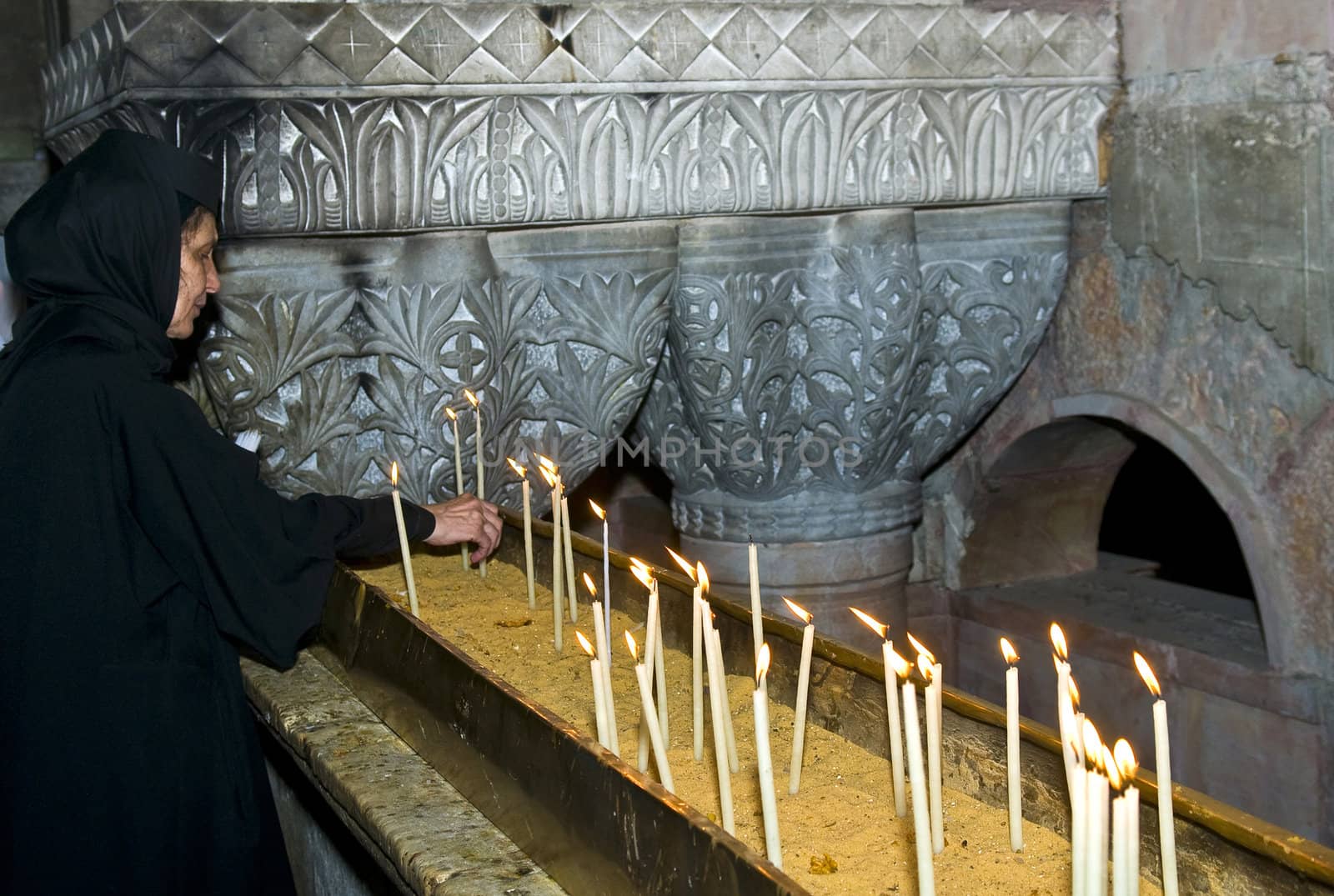 JERUSALEM - NOVEMBER 03 2011 - A pilgrim prays by candelelight in the church of the holy sepulcher in Jrusalem Israel 