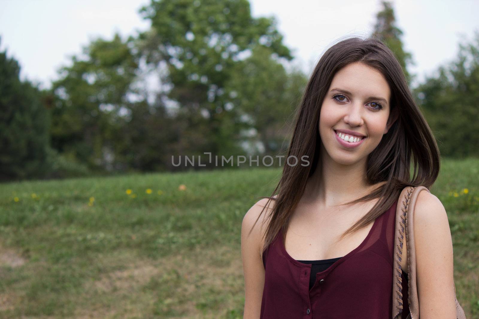 A pretty girl smiles happily in the park.