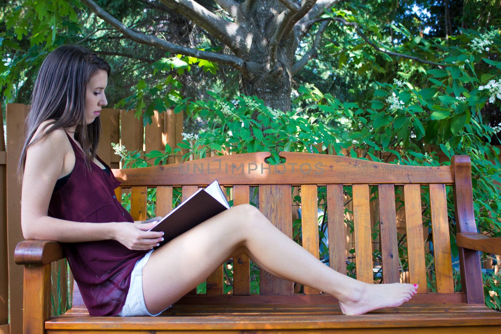 Pretty teen girl reading outside on a bench - copyspace