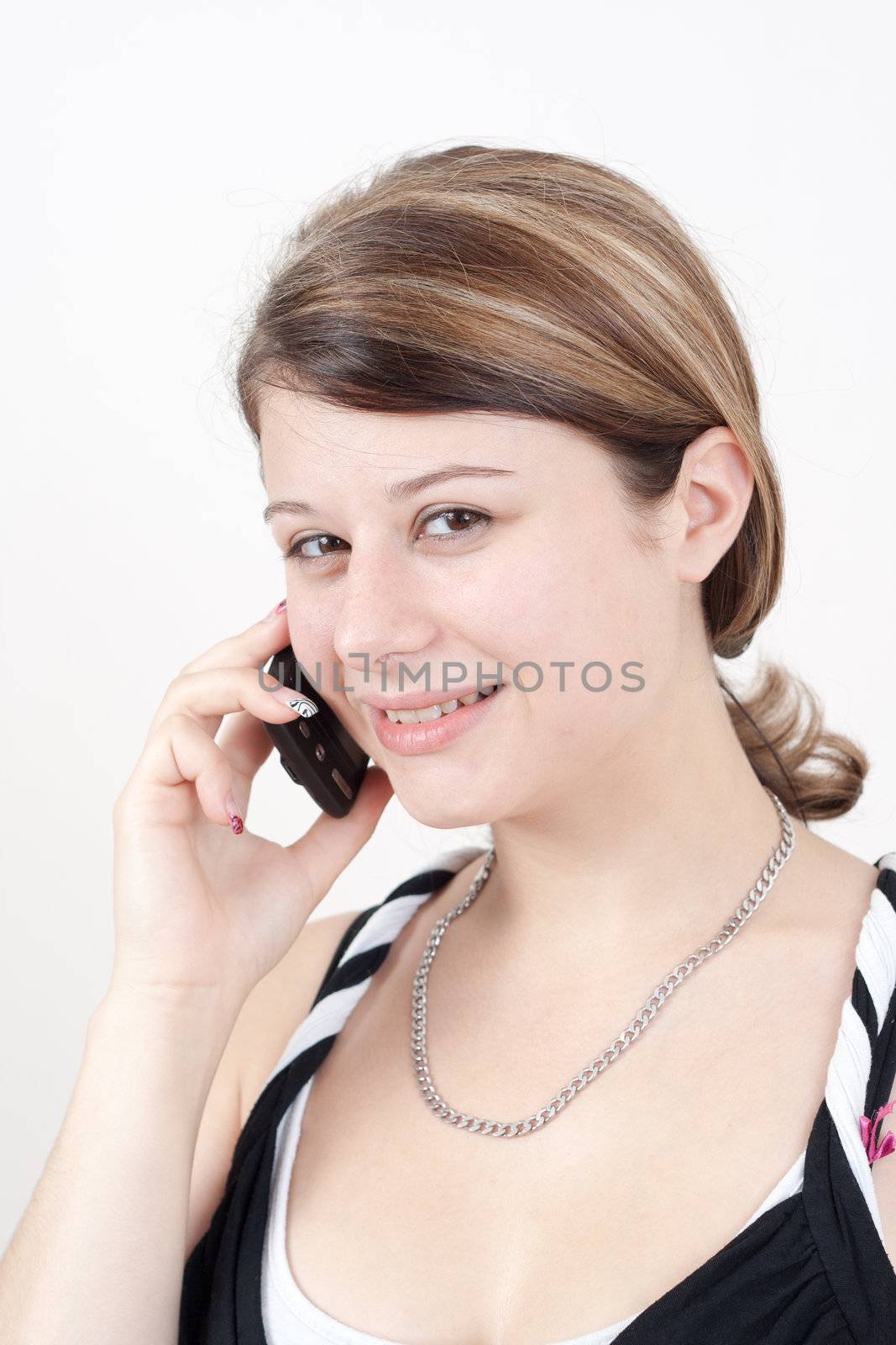 young brunette woman is talking to someone over the smartphone - isolated on white background