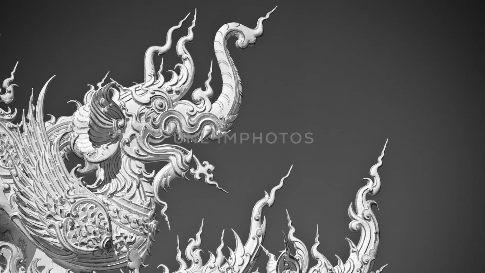 Statue of white dragon in Wat Rong Khun. Wat Rong Khun is a contemporary unconventional Buddhist temple in Chiang Rai, Chiangmai province, Thailand. It is designed in white color.