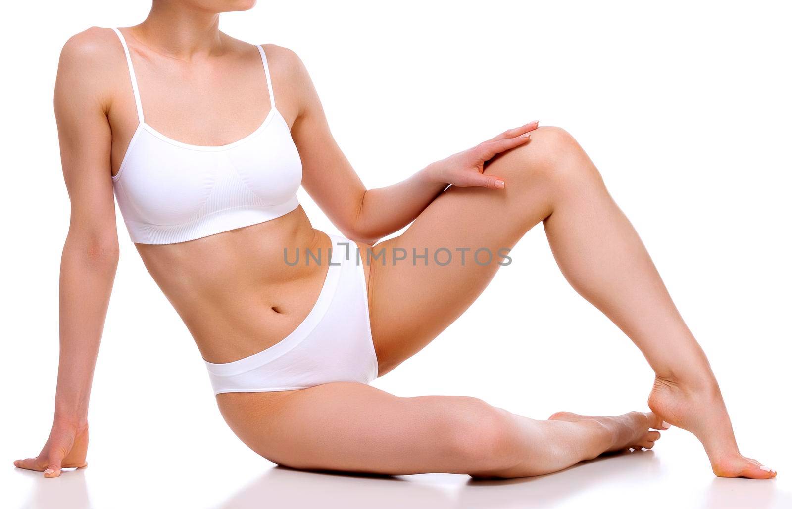 Pretty woman with slim beautiful body sitting against white background, isolated