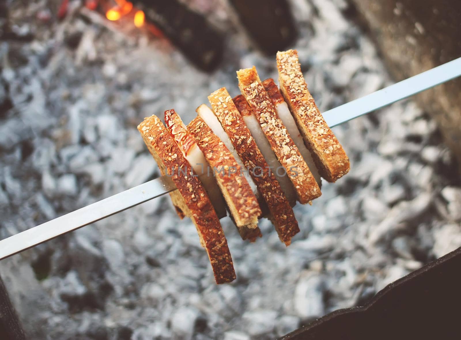 Grilling meat and bread on skewer over the brazier.