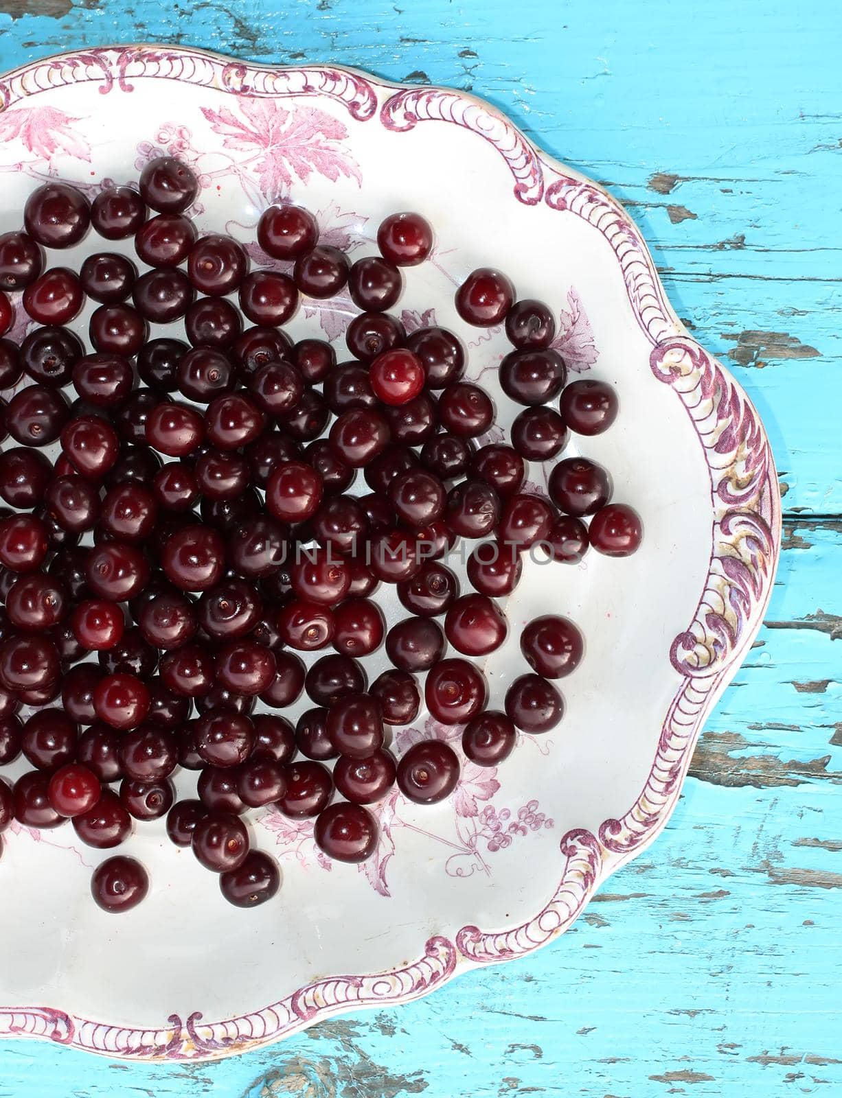 Fresh ripe cherries in a plate on wooden background by nightlyviolet