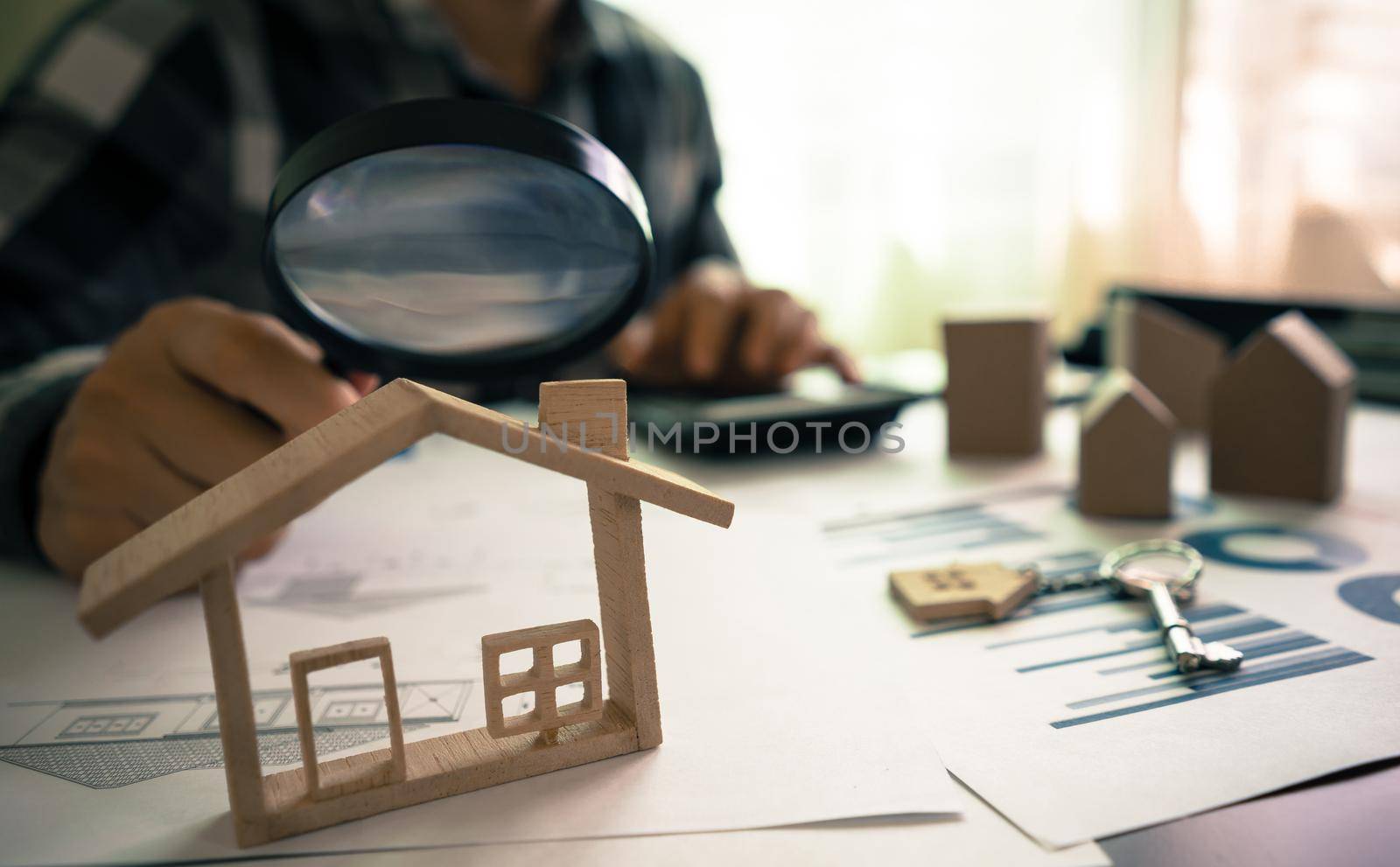 Real estate or House Appraisal using magnifying glass over the model of a wooden house. Concept of House Search for housing and apartments. by pravinrus