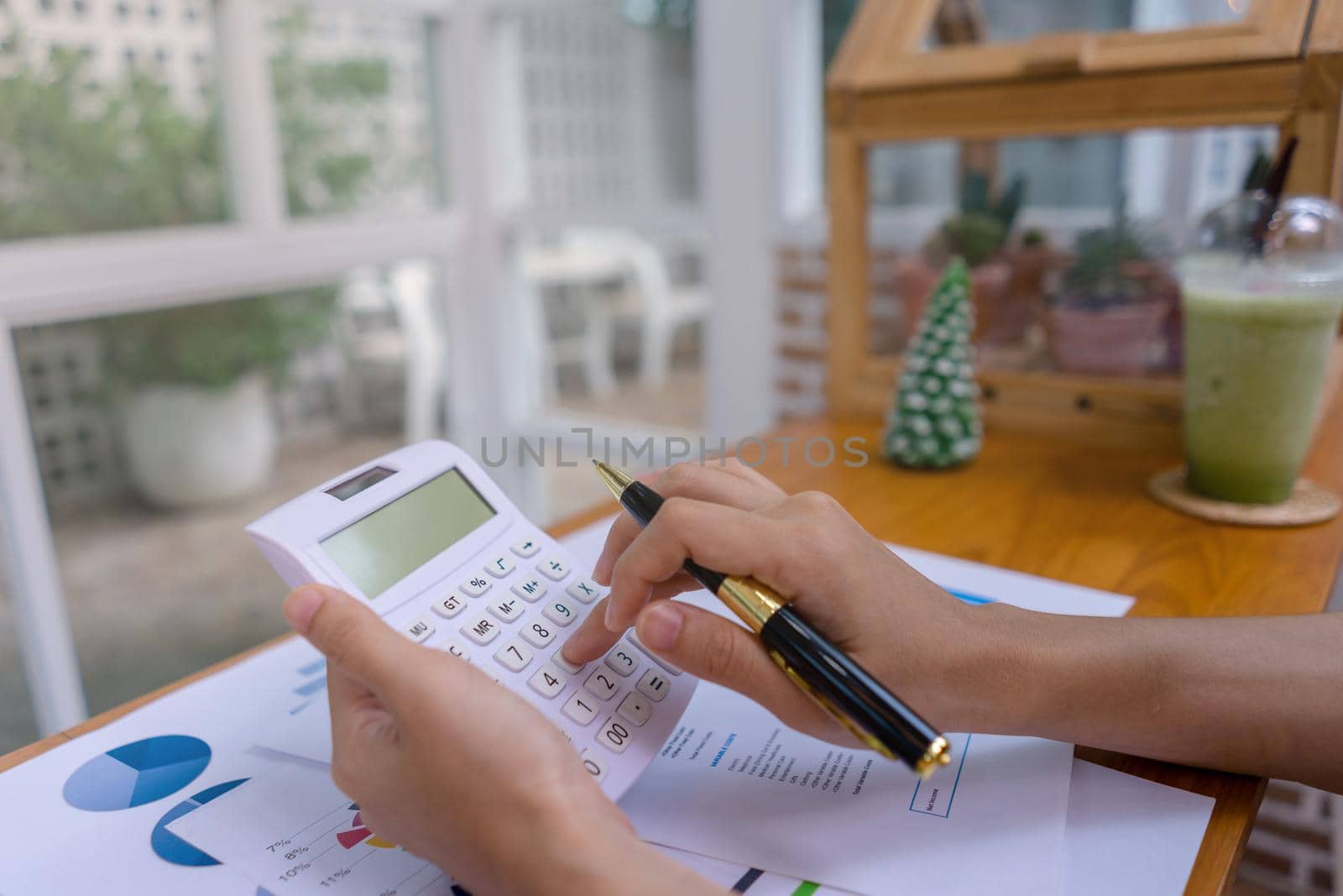 Businesswoman or accountant working with calculator, business document, business data, accountancy document, investment statistical data at smart modern office or coffee shop.