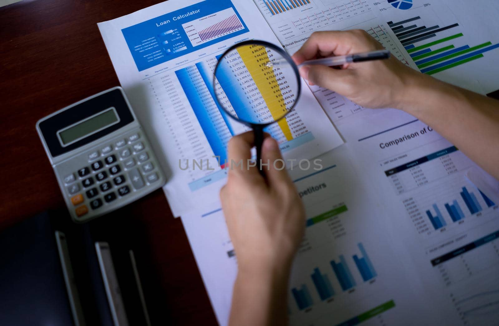 Close-up Of Auditor Hand Looking At accounting records, Auditing tax,  balance sheet, Analyzing Bill, income statistic, profit, loss Through Magnifying Glass At Workplace. by pravinrus