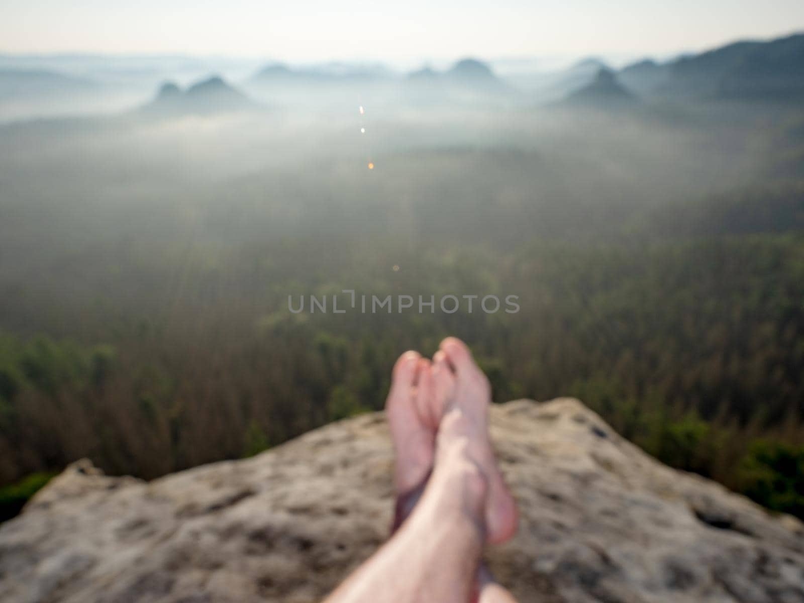 Short break on the mountain trek. Man sit or lay down on the cliff edge by rdonar2