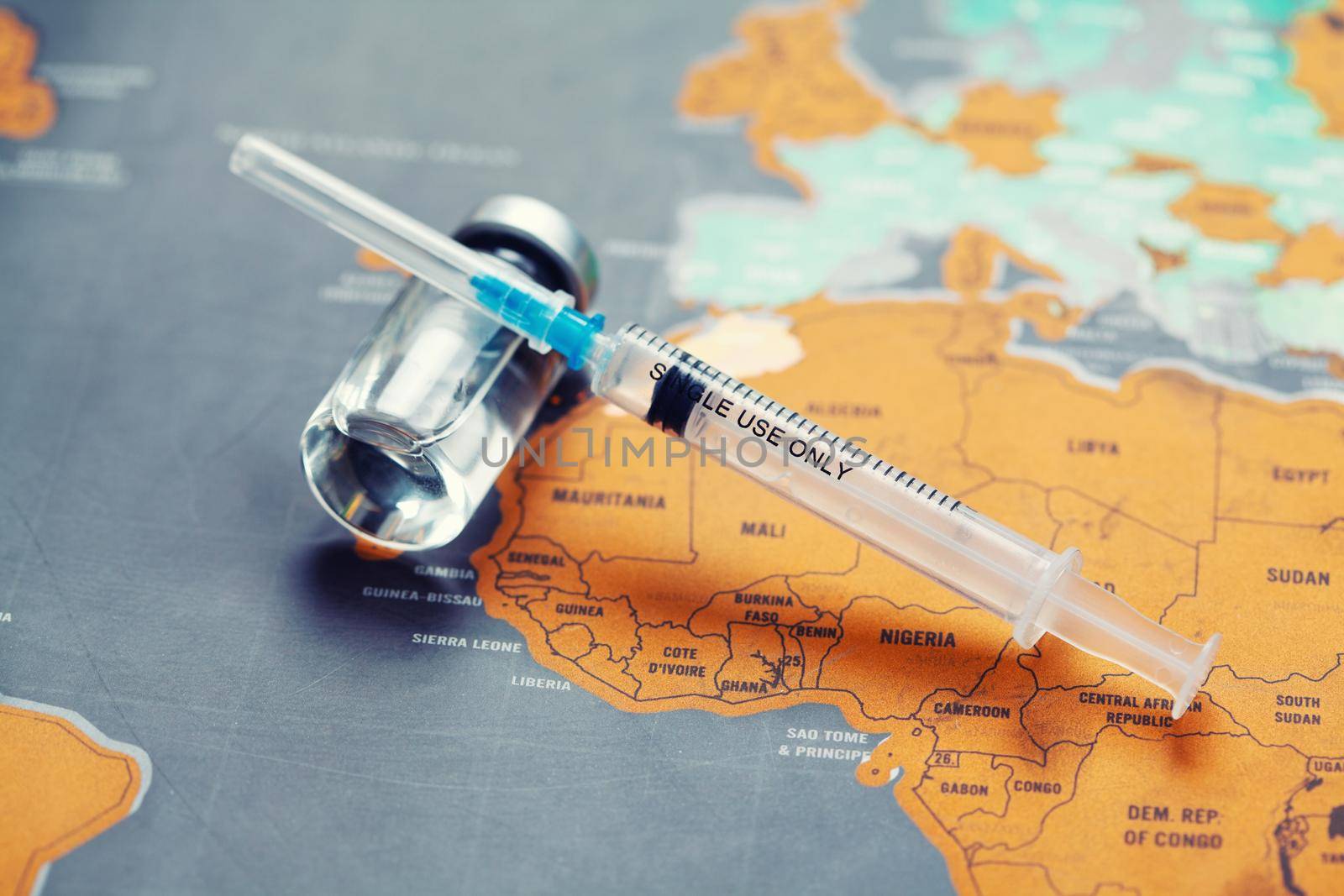 Medical syringe with a needle and a bollte with vaccine on world map. by Taut