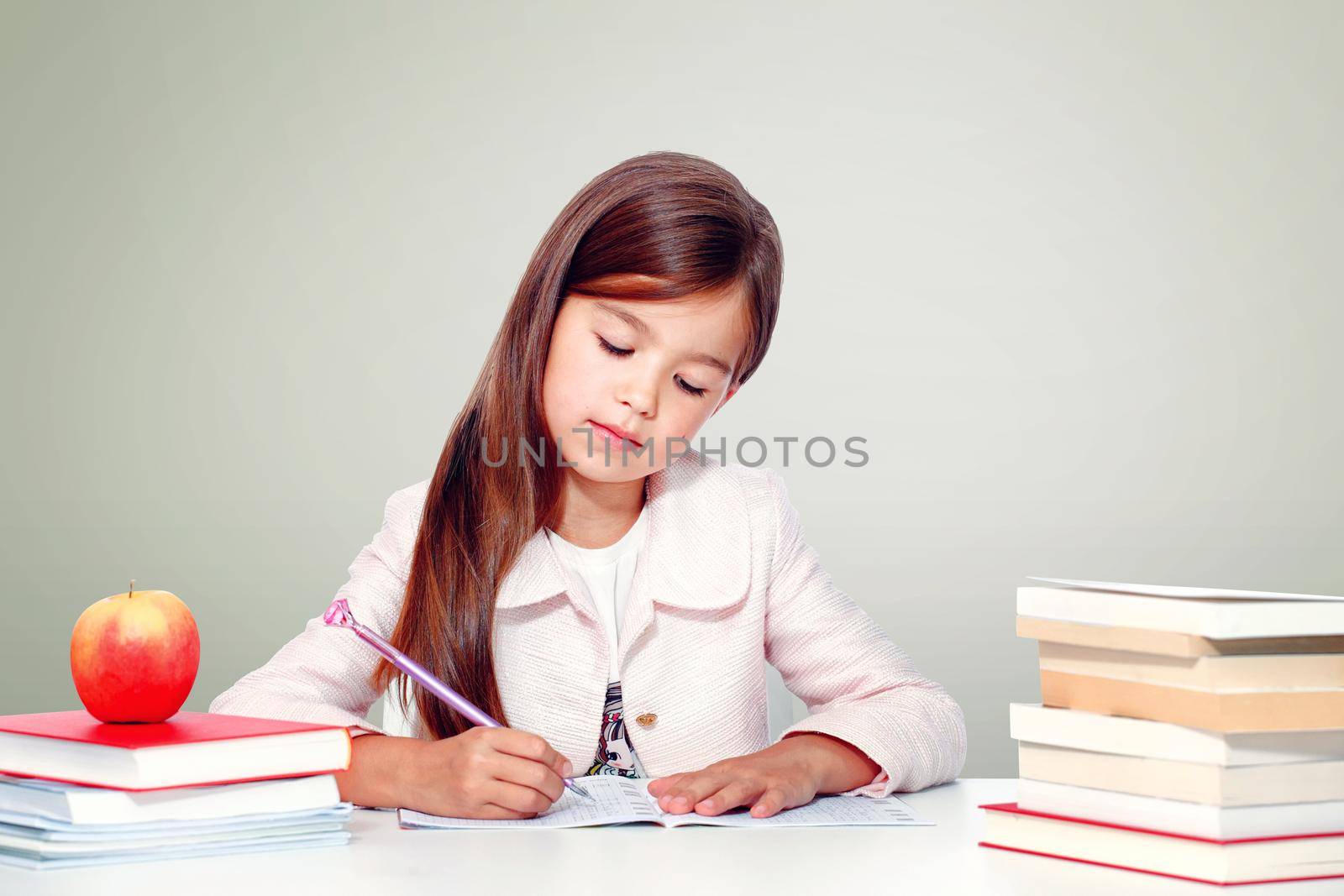 Happy and cute teen school girl writes in a book or notebook by Taut