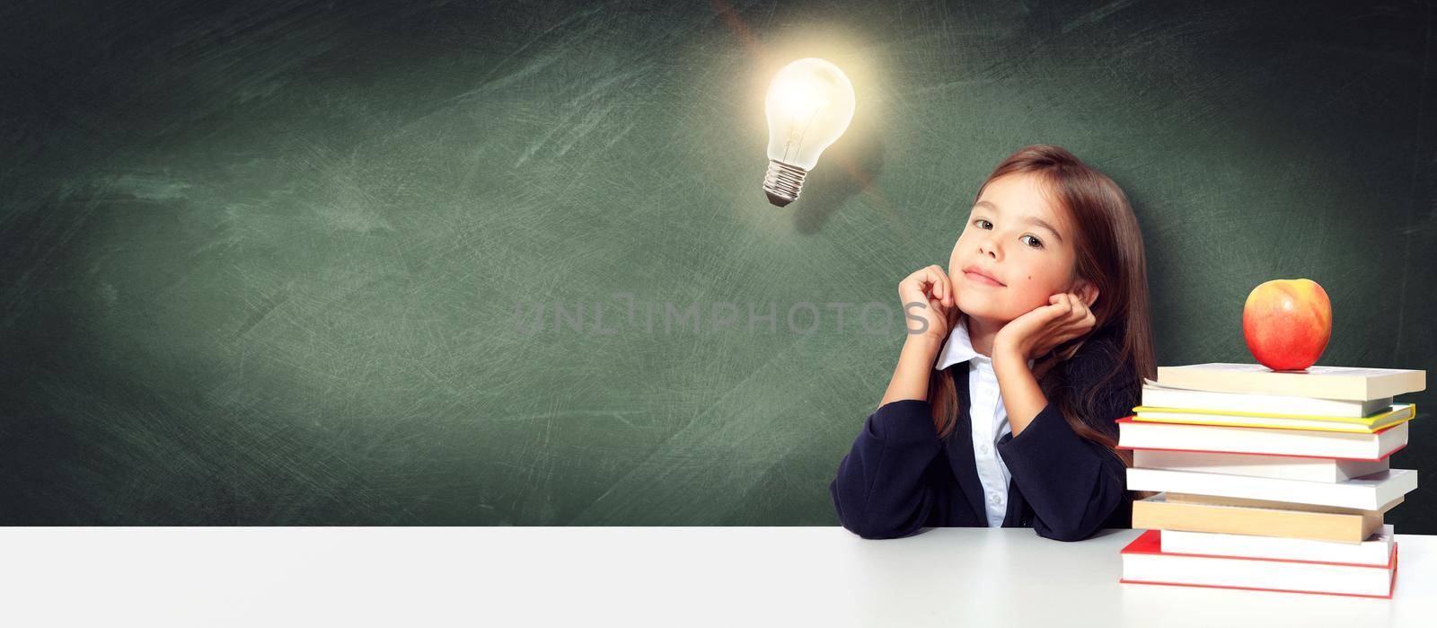 Young cute girl at chalkboard with light bulb over head by Taut