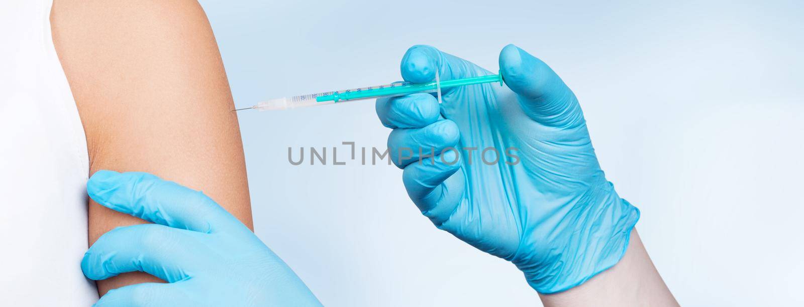 Doctor gives a syringe with vaccine to patient at clinic. by Taut