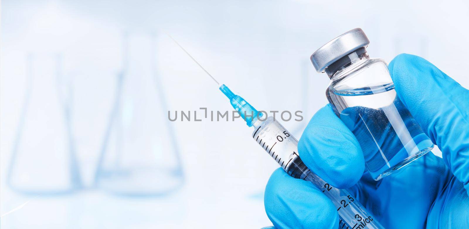 Hand holding viol with vaccine against corona virus. by Taut