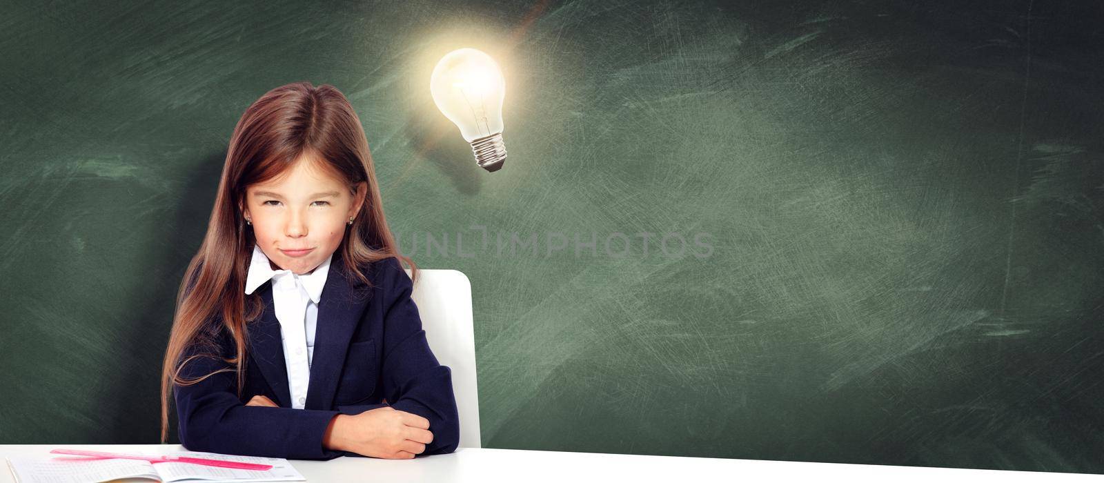 Young cute girl at chalkboard with light bulb over head by Taut