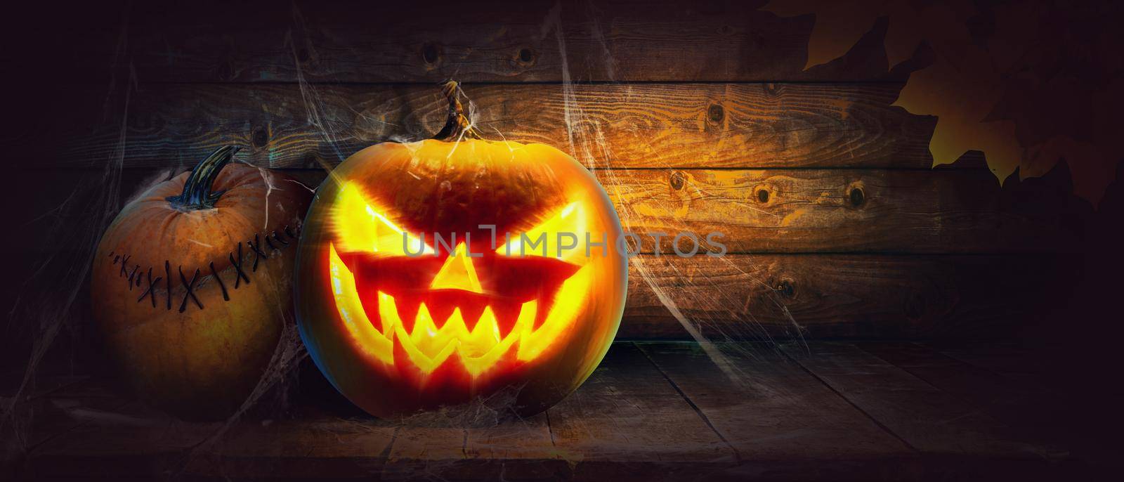 Scary Halloween pumpkin with eyes glowing inside on wooden background by Taut