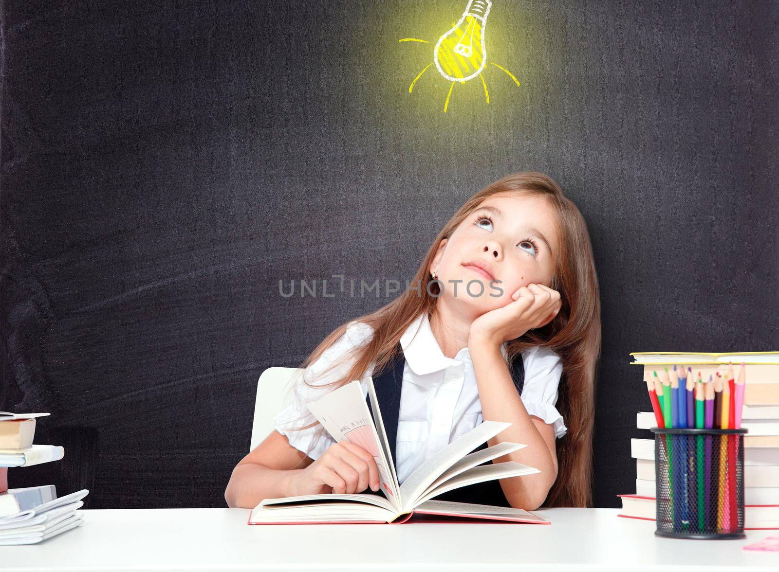 Young cute girl at chalkboard with light bulb over head by Taut