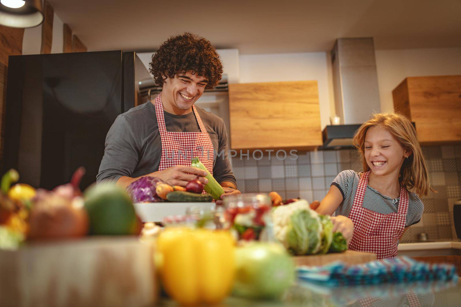 Happy father and his daughter enjoy and having fun in making and having healthy meal together at their home kitchen.