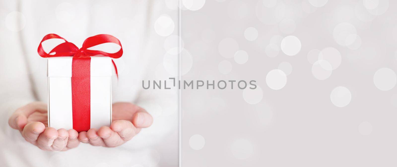 Gift box in wrapping paper with satin ribbon. Merry Christmas holiday concept.