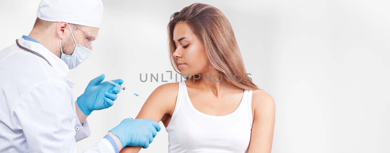 Doctor gives a syringe with vaccine to patient at clinic. by Taut