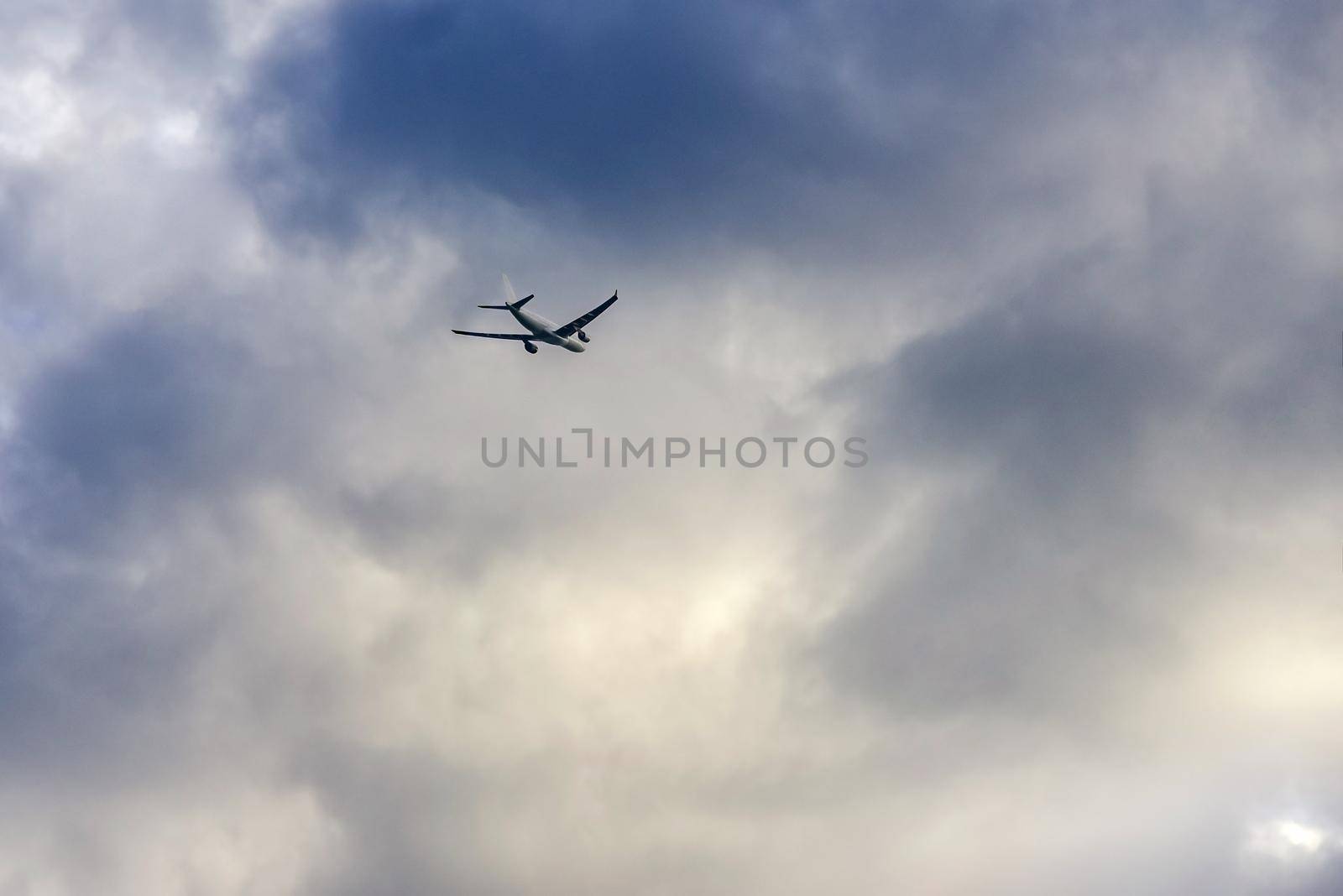 A passenger plane flies towards the thunderclouds.
