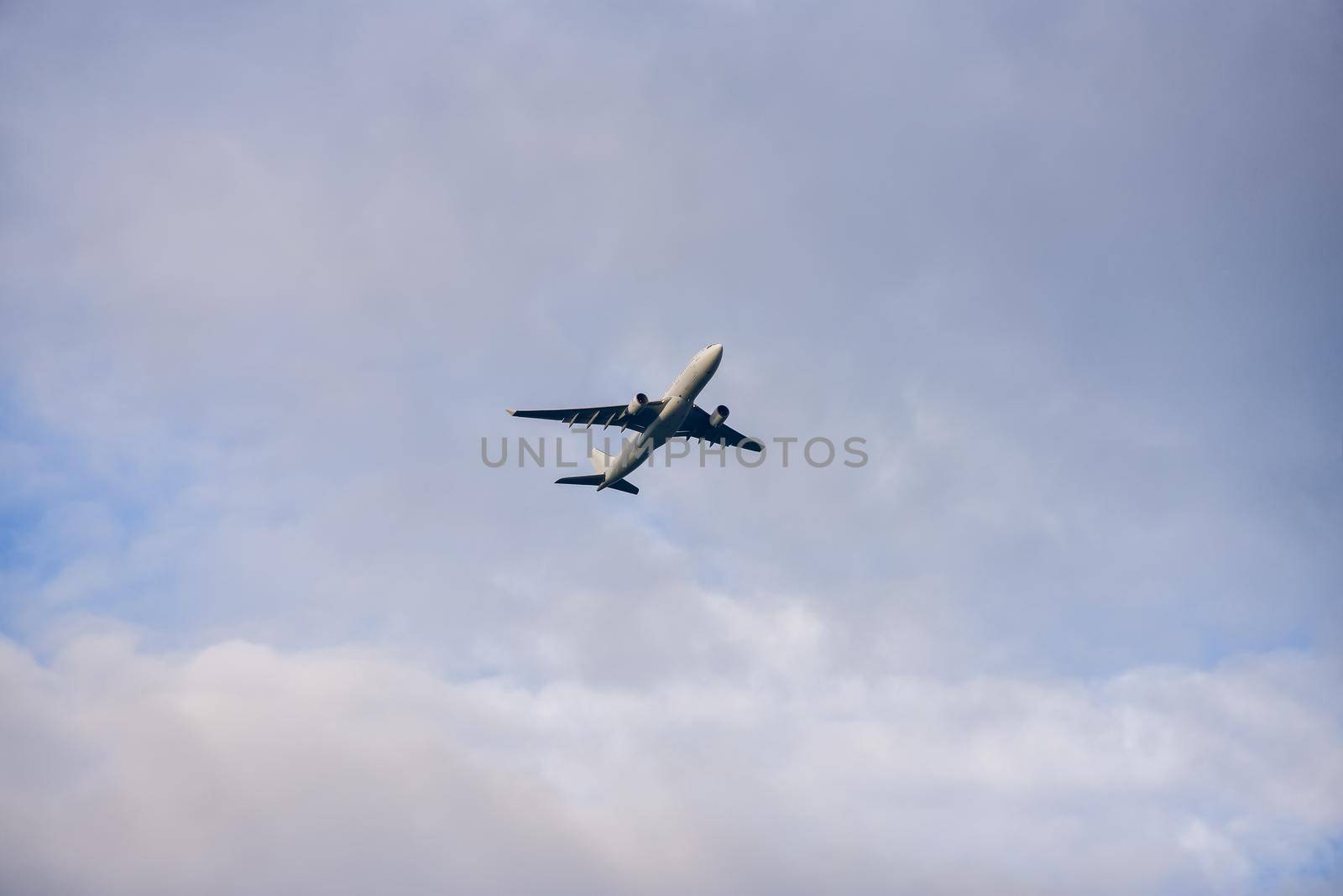 Passenger airplane flying against the cloudy sky.