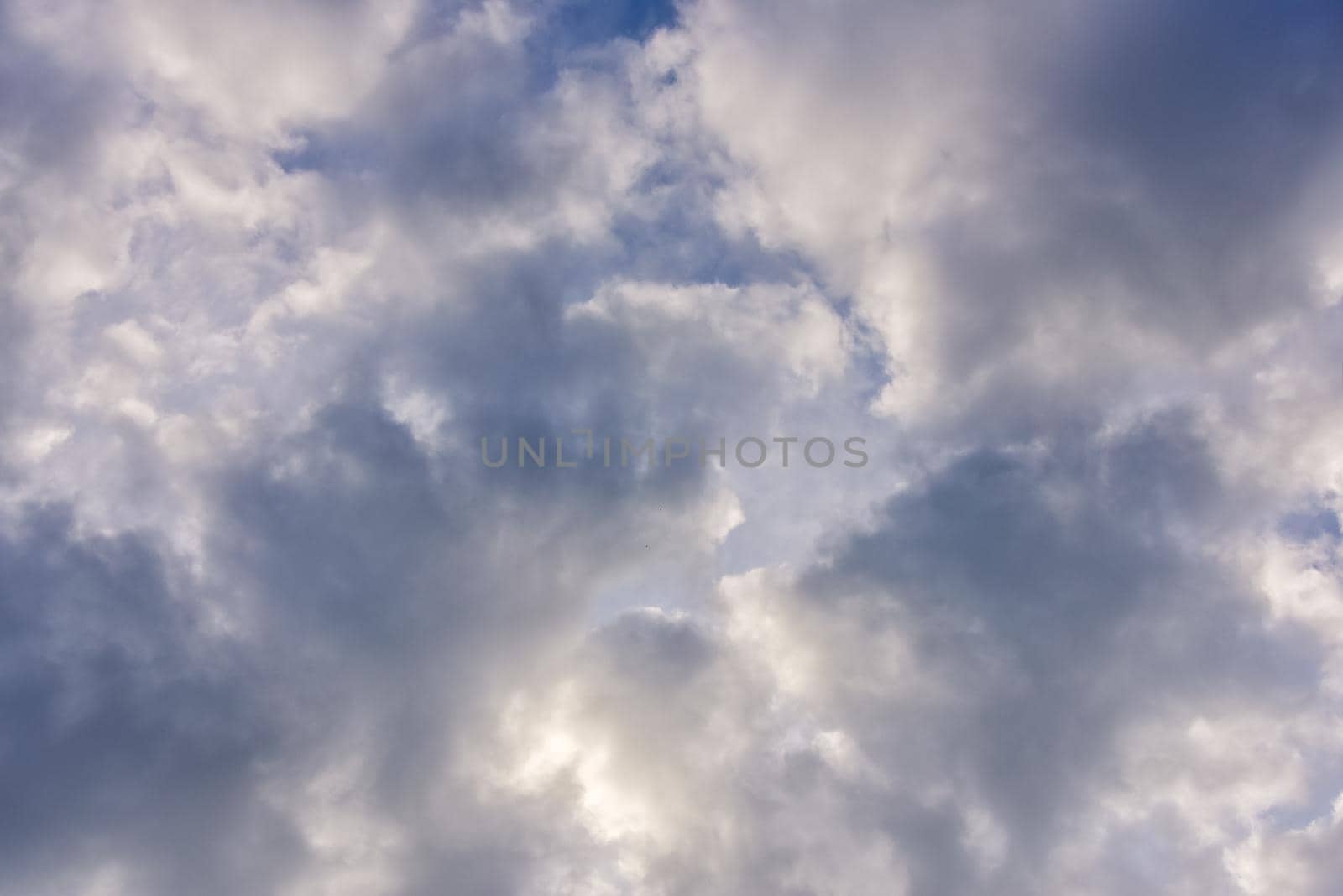 blue sky background with cumulus white clouds and looming storm clouds.