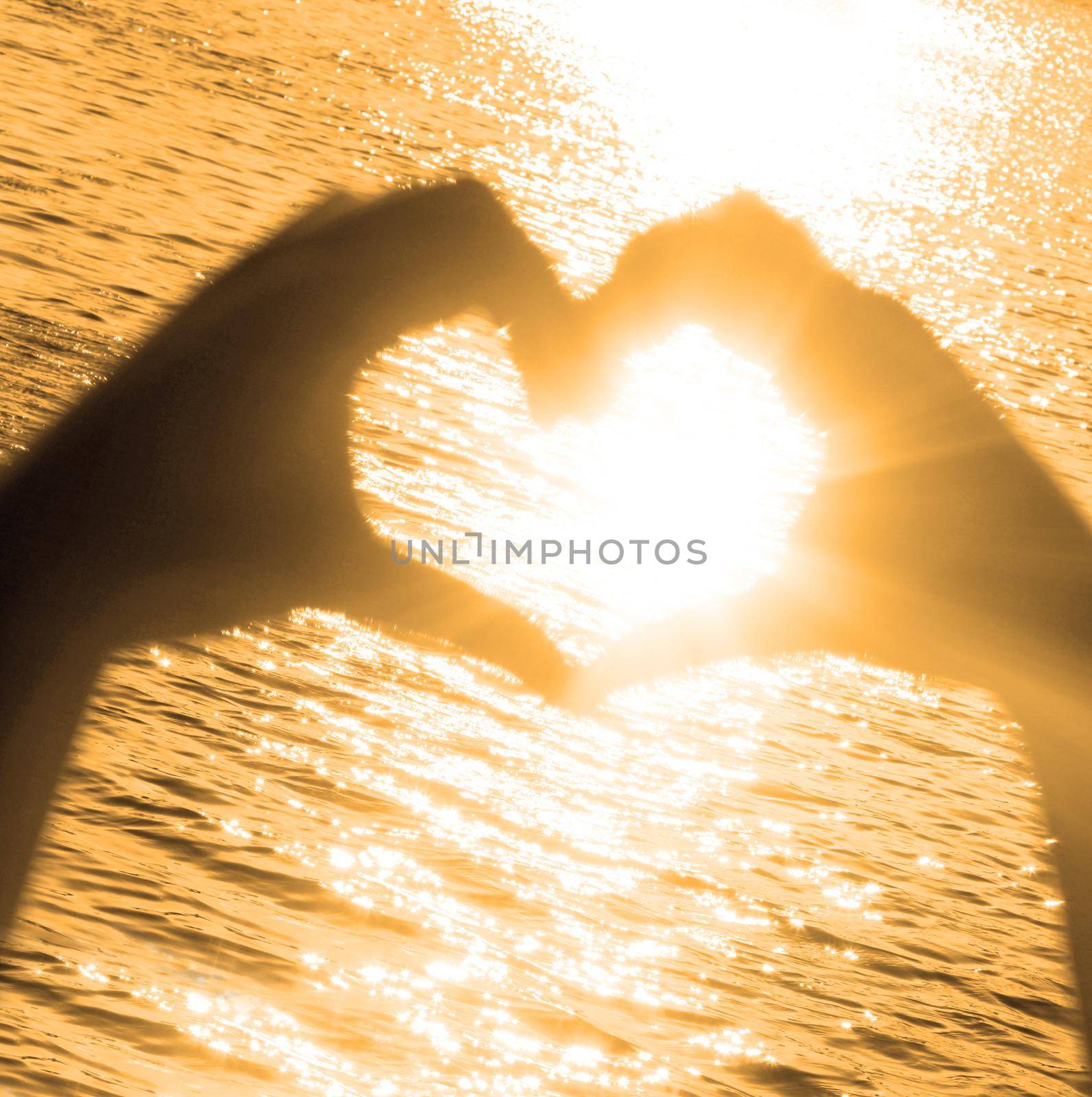 Hand shaped heart against sunset. Valentines day concept by Taut