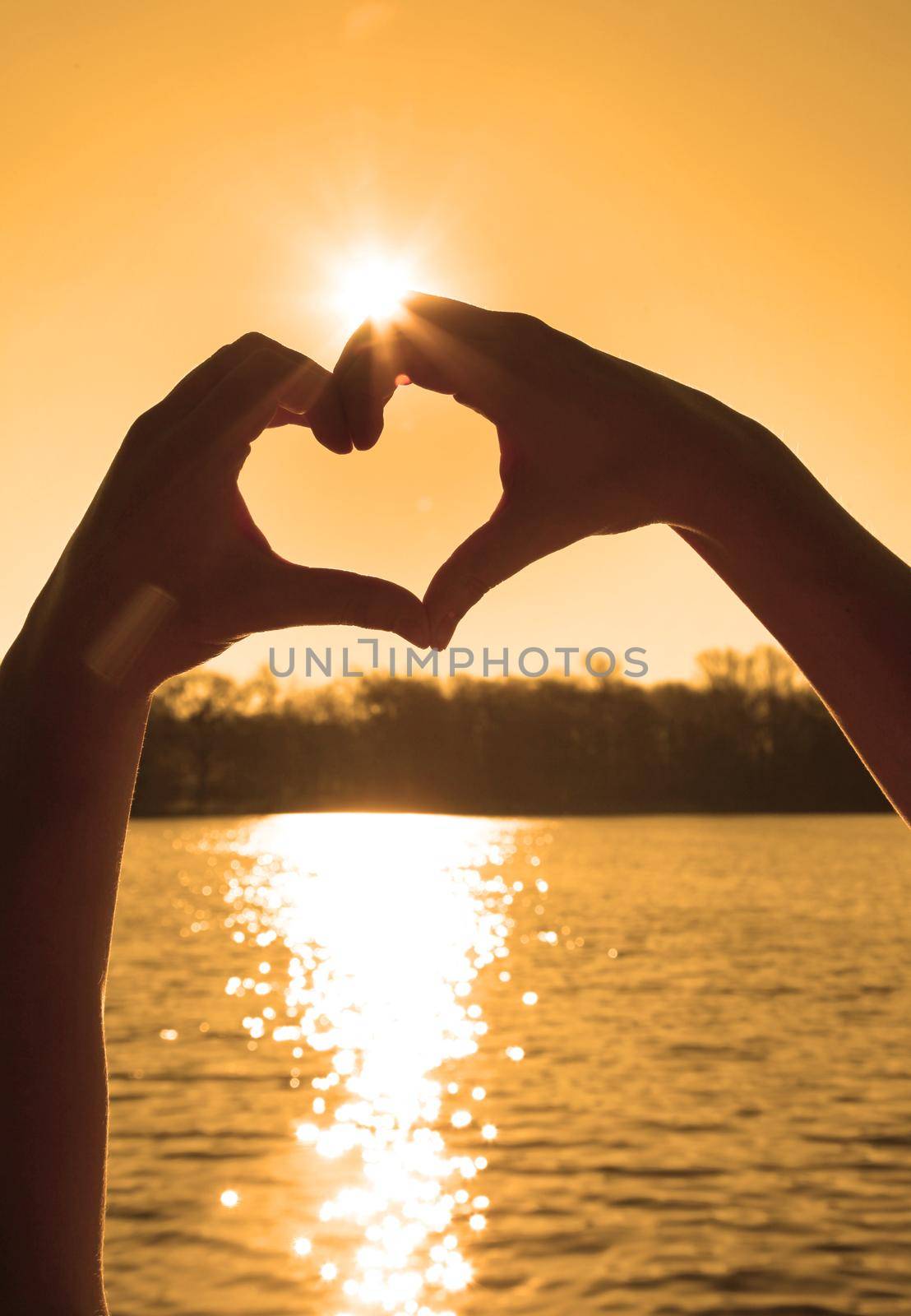 Hand shaped heart against sunset. Valentines day concept by Taut