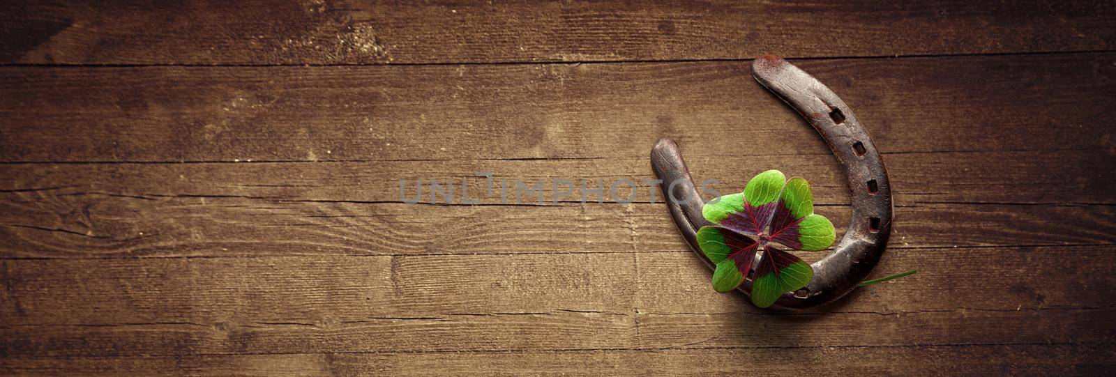 Horseshoe with lucky clover on a wooden background by Taut